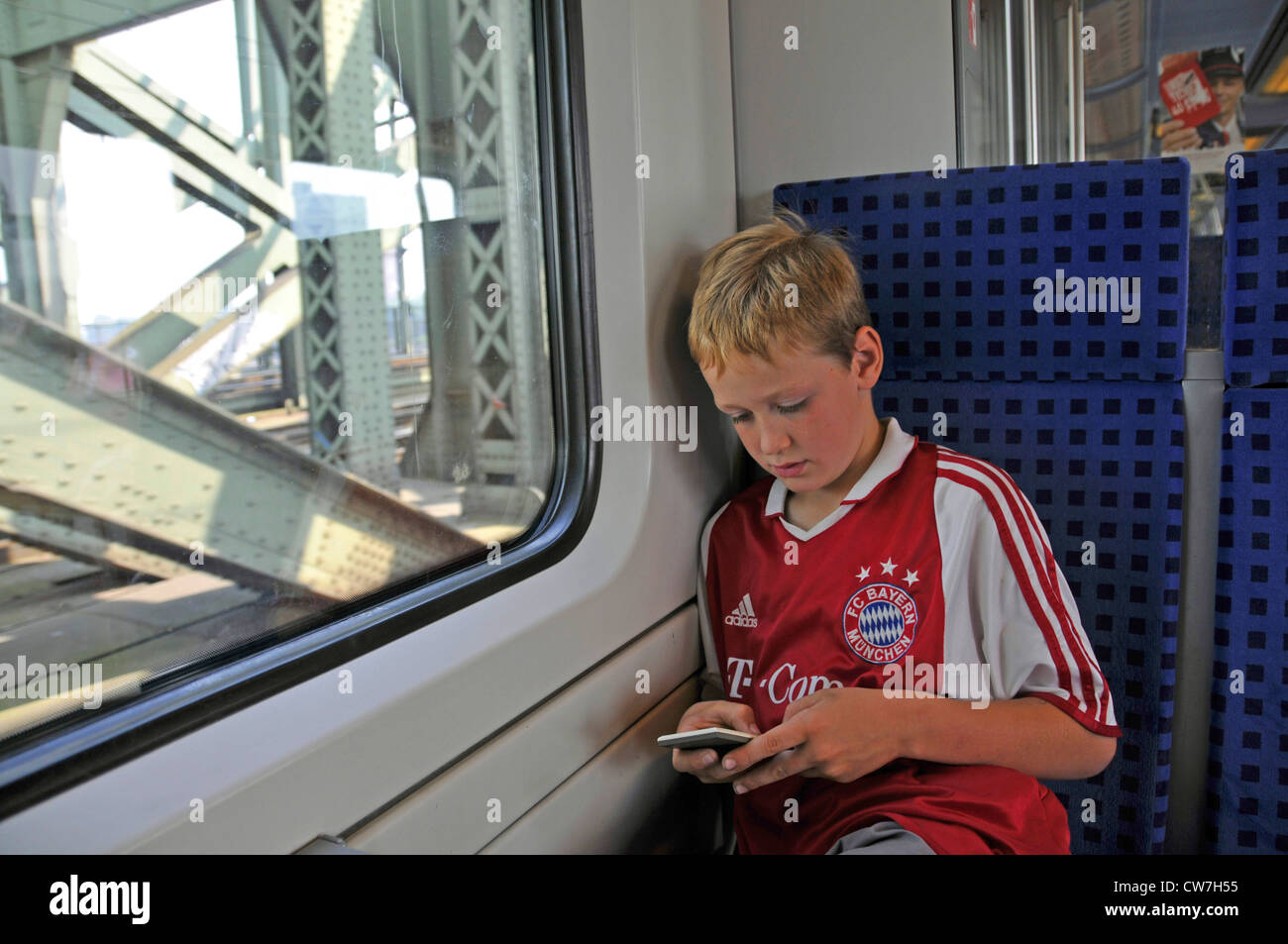 boy sitting in a train playing with his Iphone, Germany Stock Photo