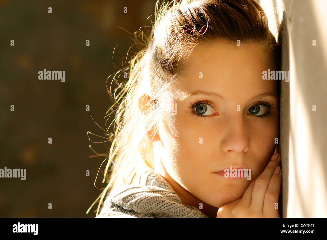 young blond woman leaning against a wall Stock Photo