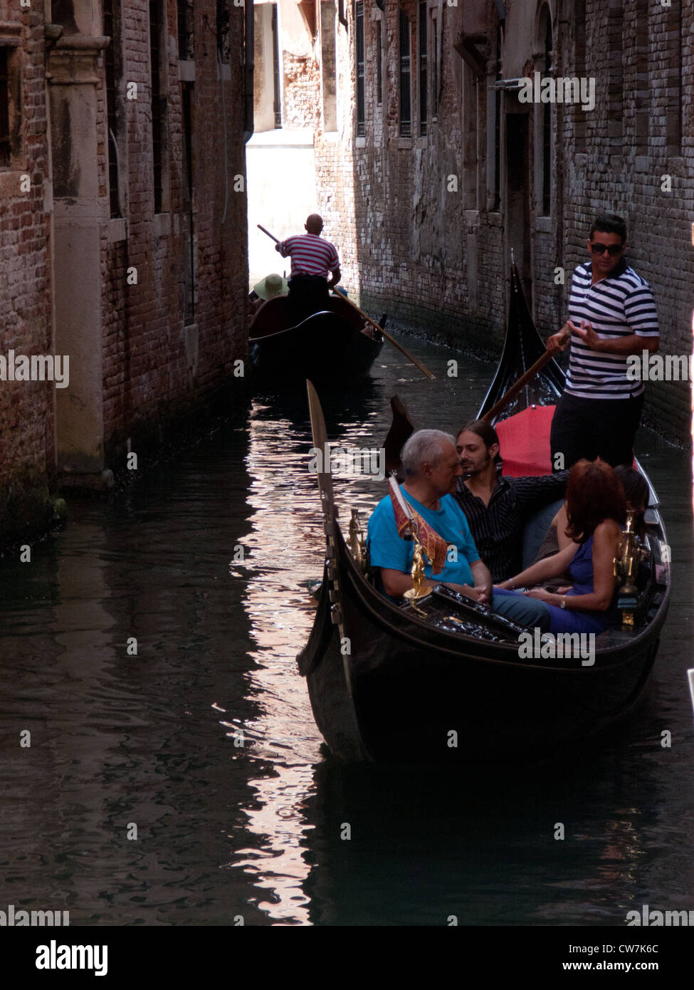 Tourists enjoy a gondola trip on a canal in Venice, Italy Stock Photo