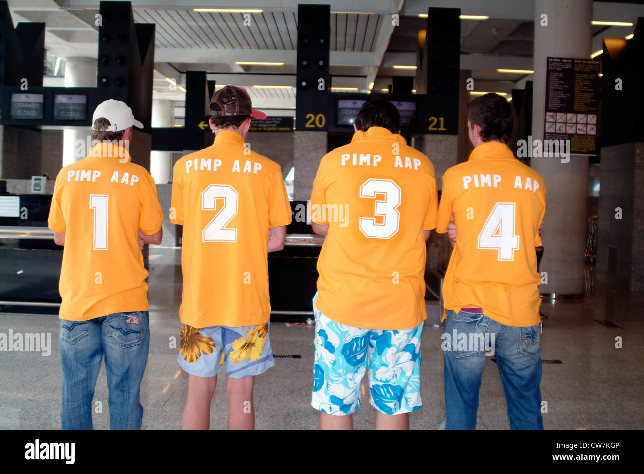 four tourists with consecutively numbered t-shirts waiting for luggage at airport, Spain, Balearen, Majorca Stock Photo
