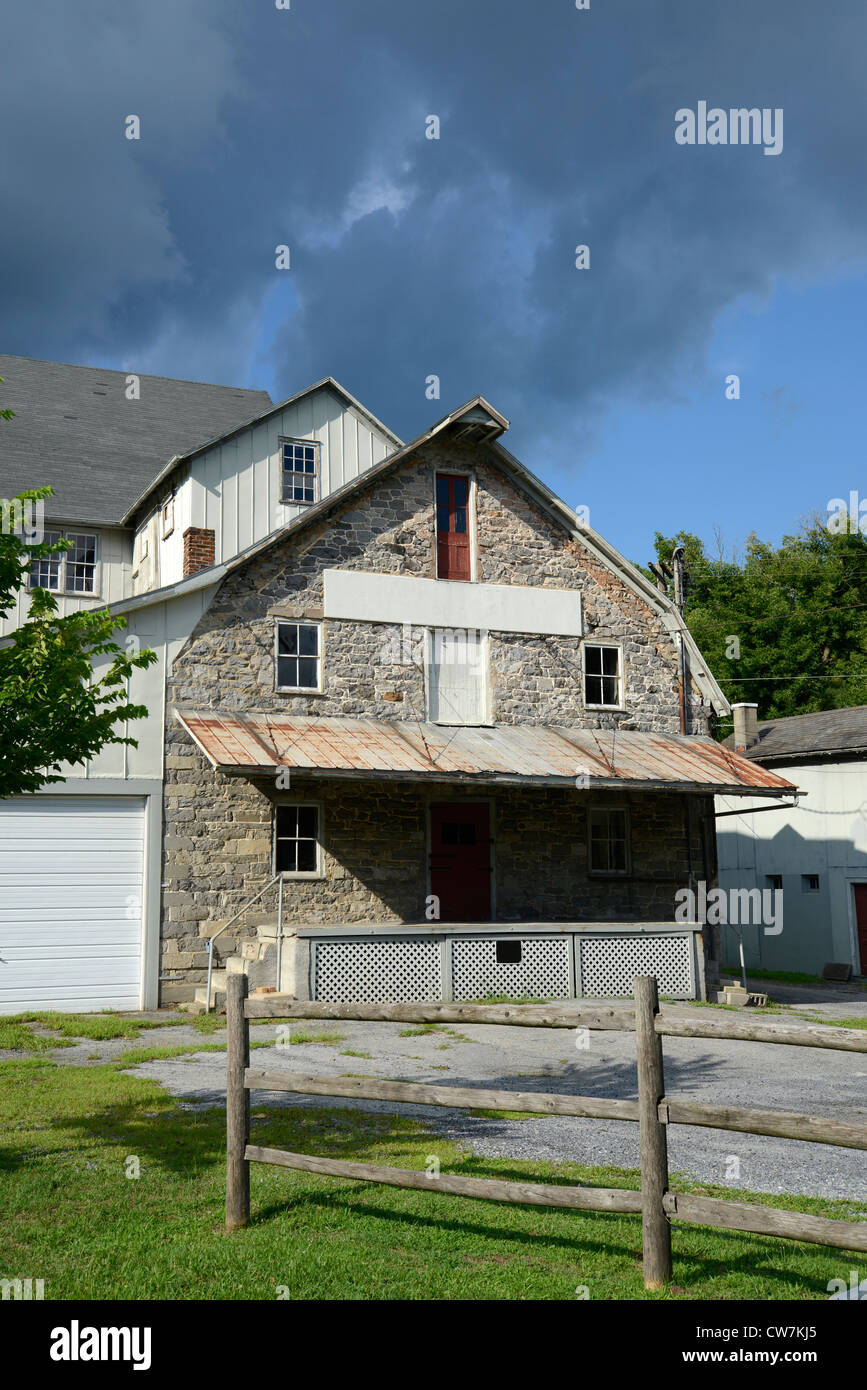 exterior of an old stone feed mill by a wood split rail fence Stock Photo