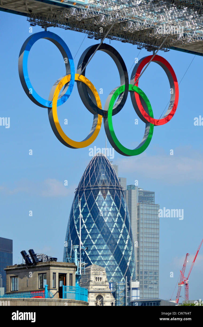 Retractable Olympic rings in down position below Tower Bridge high level walkway with Gherkin London landmark skyscraper with Heron Tower England UK Stock Photo