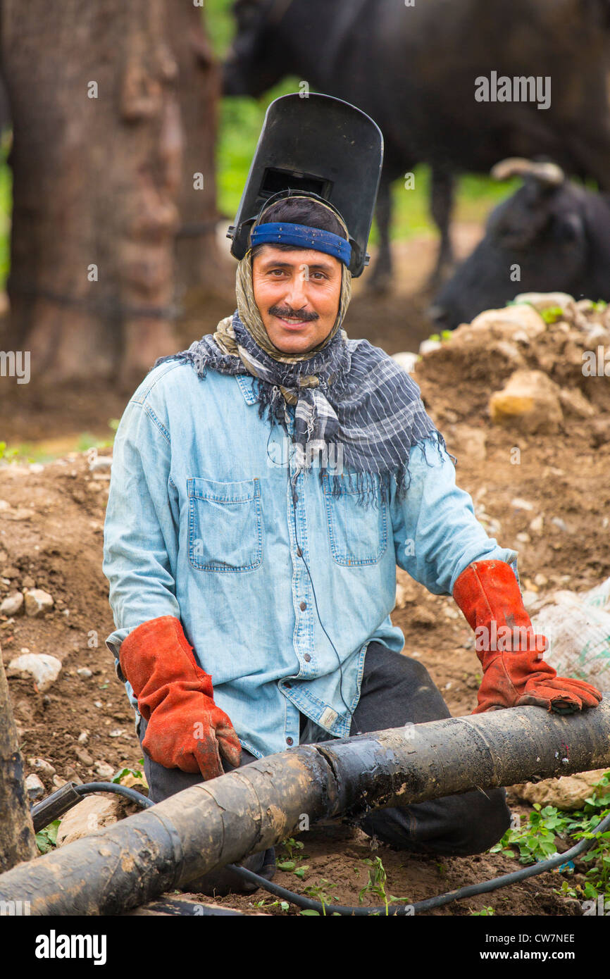 Man welding an underground pipe in Said Pur Village, Islamabad