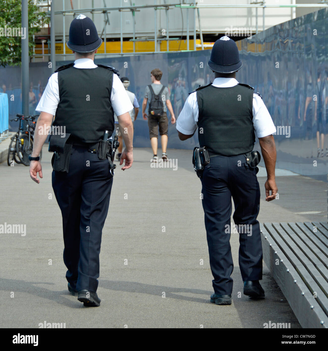 Back view of white & black policeman officer in summer traditional uniform & helmet on Metropolitan Police foot patrol in Southwark London England UK Stock Photo