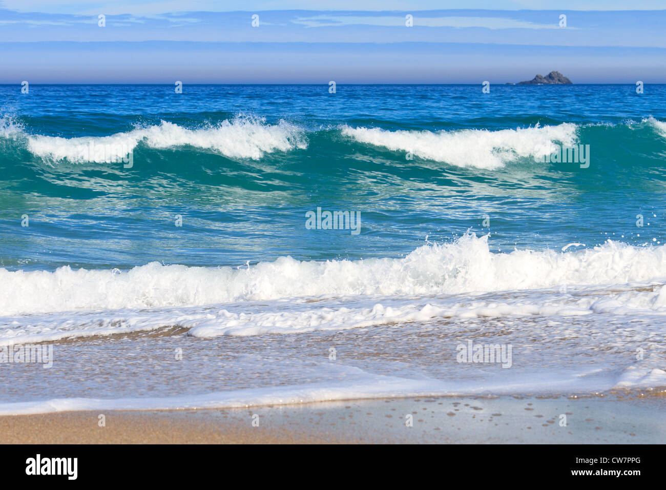 Waves crashing on the beach at Whitesands bay in Cornwall with The Brisons on the horizon Stock Photo