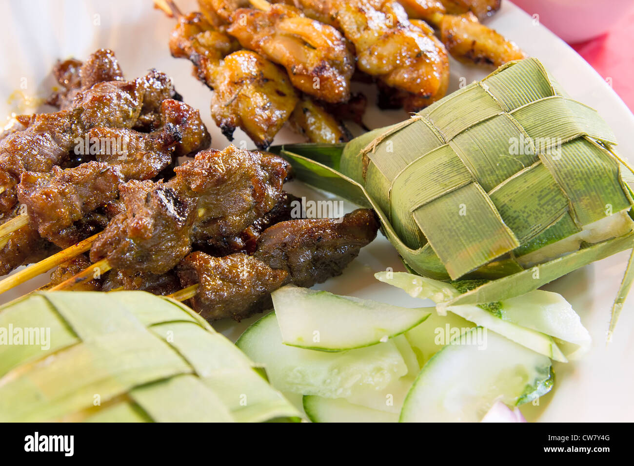 Chicken Beef and Mutton Satay with Ketupat and Cucumbers Closeup Stock Photo