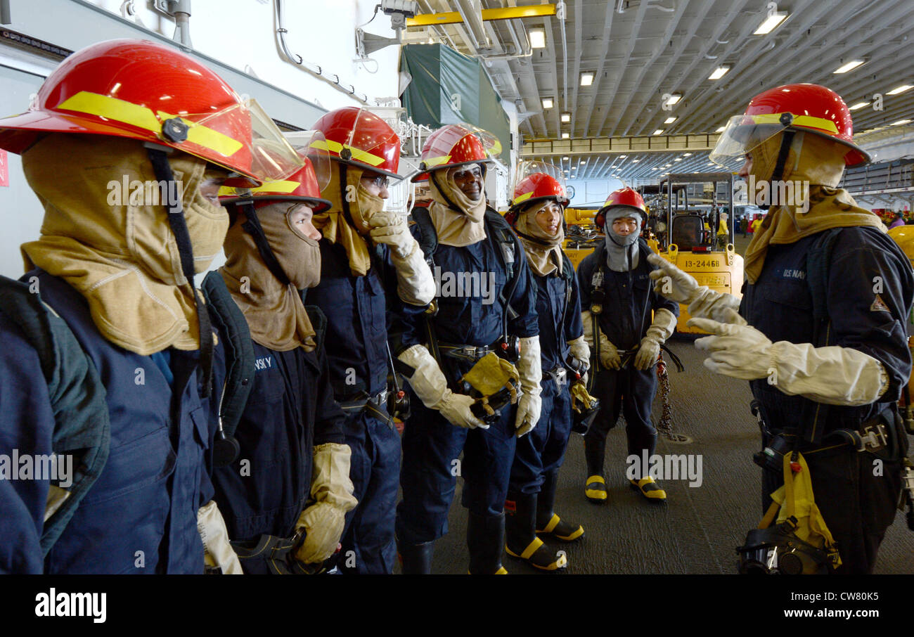 A five-man-hose team prepares for a firefighting simulation during a General Quarters drill aboard the forward-deployed amphibious assault ship USS Bonhomme Richard (LHD 6). Bonhomme Richard, commanded by Capt. Daniel Dusek, is the lead of the forward-deployed amphibious ready group. Stock Photo