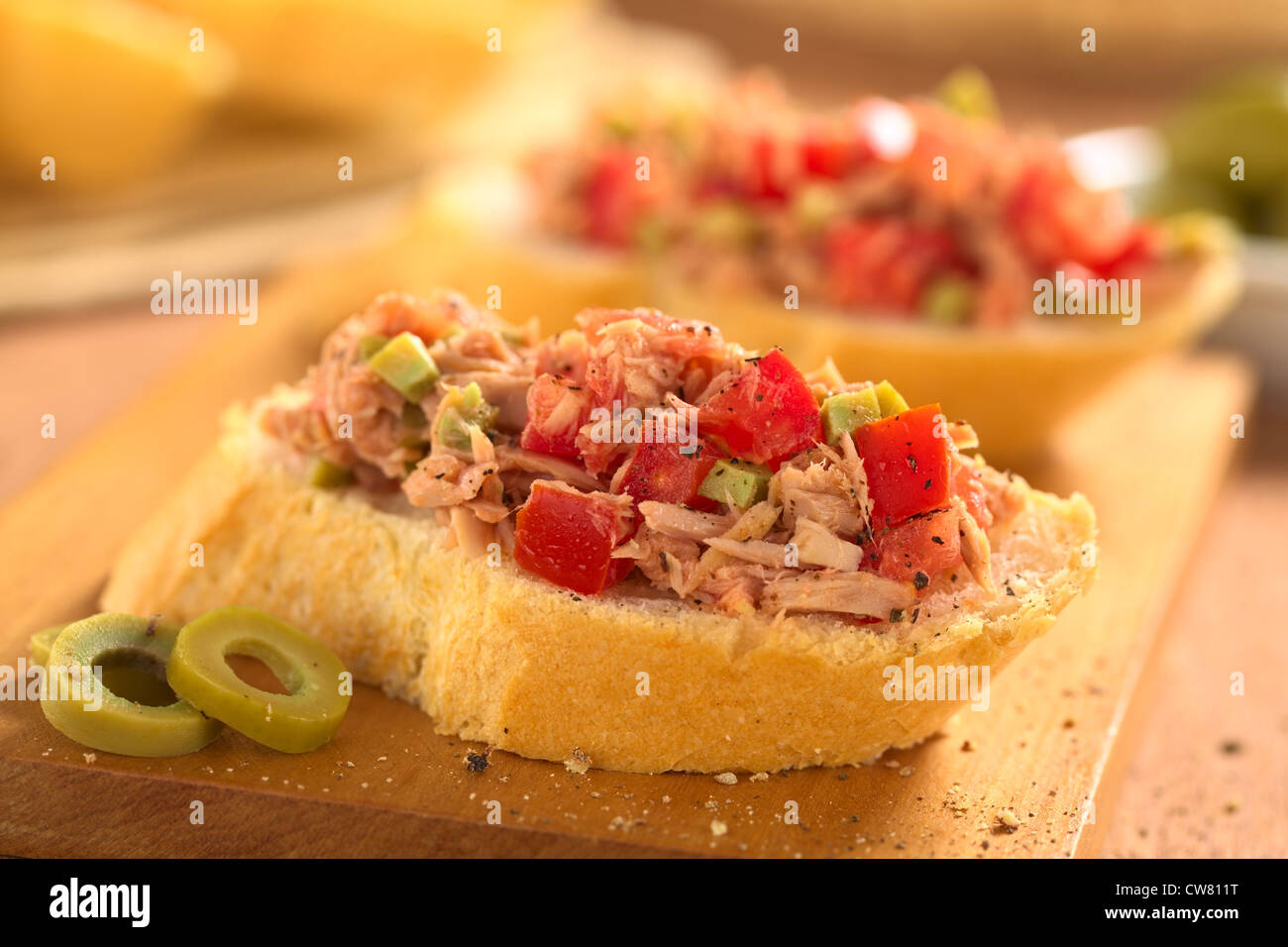 Slice of baguette with fresh tuna, green olive and tomato spread
