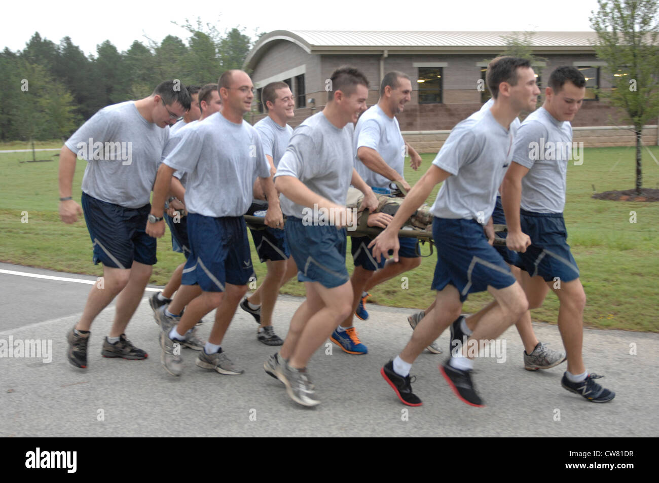 Airmen from 20th Civil Engineering Squadron, Explosive Ordinance Disposal run together carrying a dummy during the 5K Poker Run at Shaw Air Force Base, S.C., Aug. 10, 2012. They trained carrying the dummy to promote team work and practiced the concept “never leave an Airman behind.” To support that belief, they carried the dummy through the entire 3 ½ mile race. Stock Photo