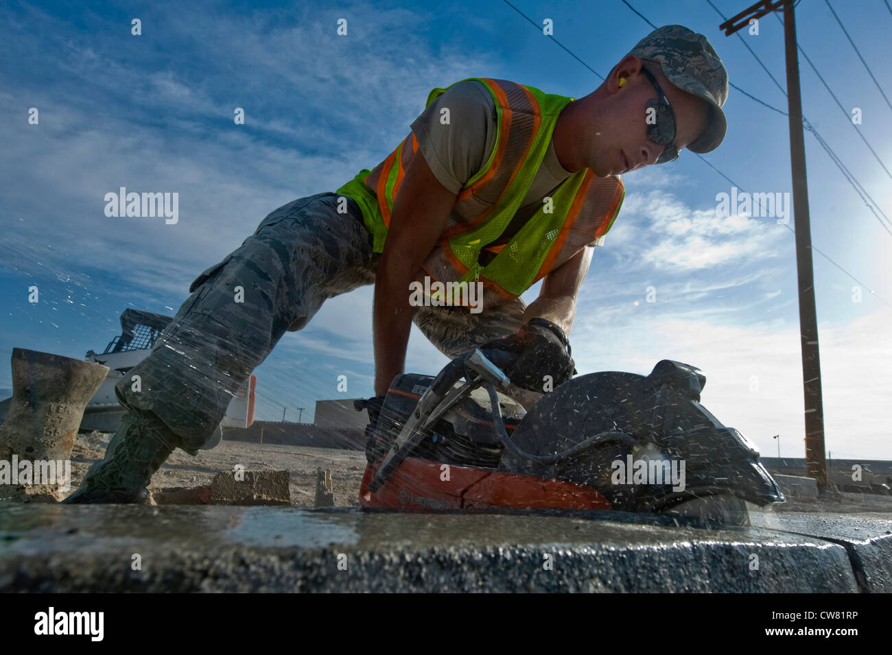 U.S. Air Force Senior Airman Andrew Higginbotham, 99th Civil Engineer Squadron heavy equipment and pavements journeyman, uses a concrete saw to cut out a piece of curb during the construction of a parking lot Aug.15,2012, at Nellis Air Force Base, Nev. The parking lot will be a general parking lot for work centers around the area and can be used for events held on base. Stock Photo