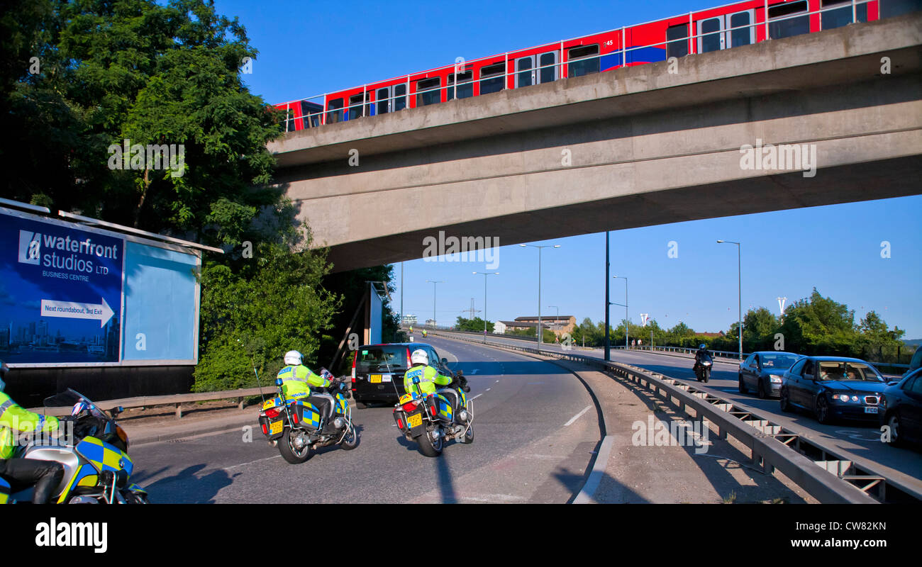 Police escorting VIPs to Olympics venue in Excel showing Docklands Light Railway (DLR) in transit at Lower Lea Crossing. Stock Photo