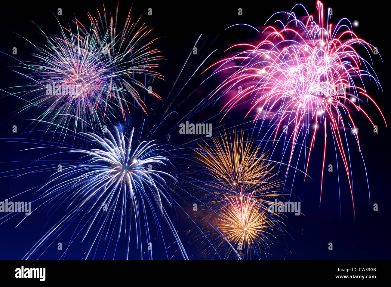 Fireworks of several colors bursting against a dark blue sky Stock Photo
