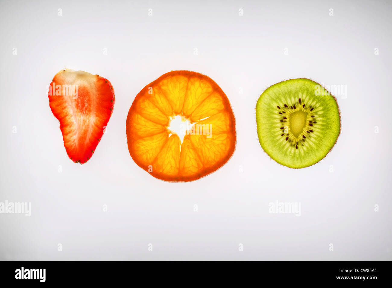 Fruit slices. Strawberry orange and kiwi fruit sliced thinly and backlit. Stock Photo