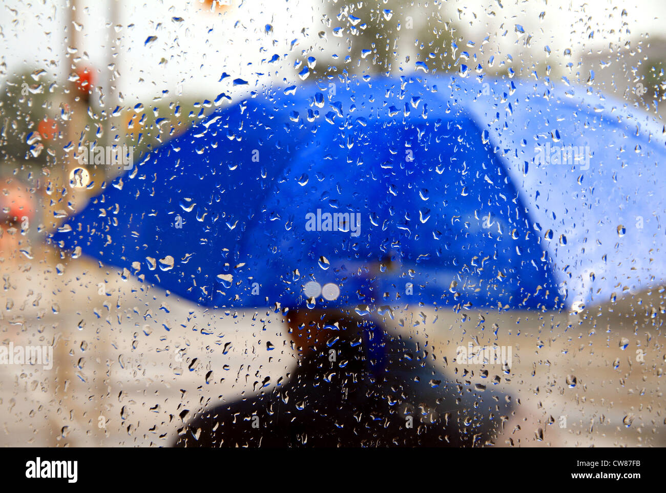 A man holding a blue umbrella during a rainy day Stock Photo - Alamy