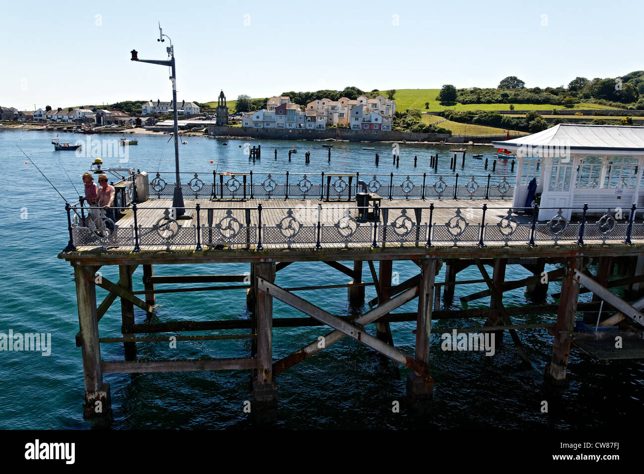Two men fishing from the end of Swanage pier with modern housing at Pevril Point in the background. Stock Photo