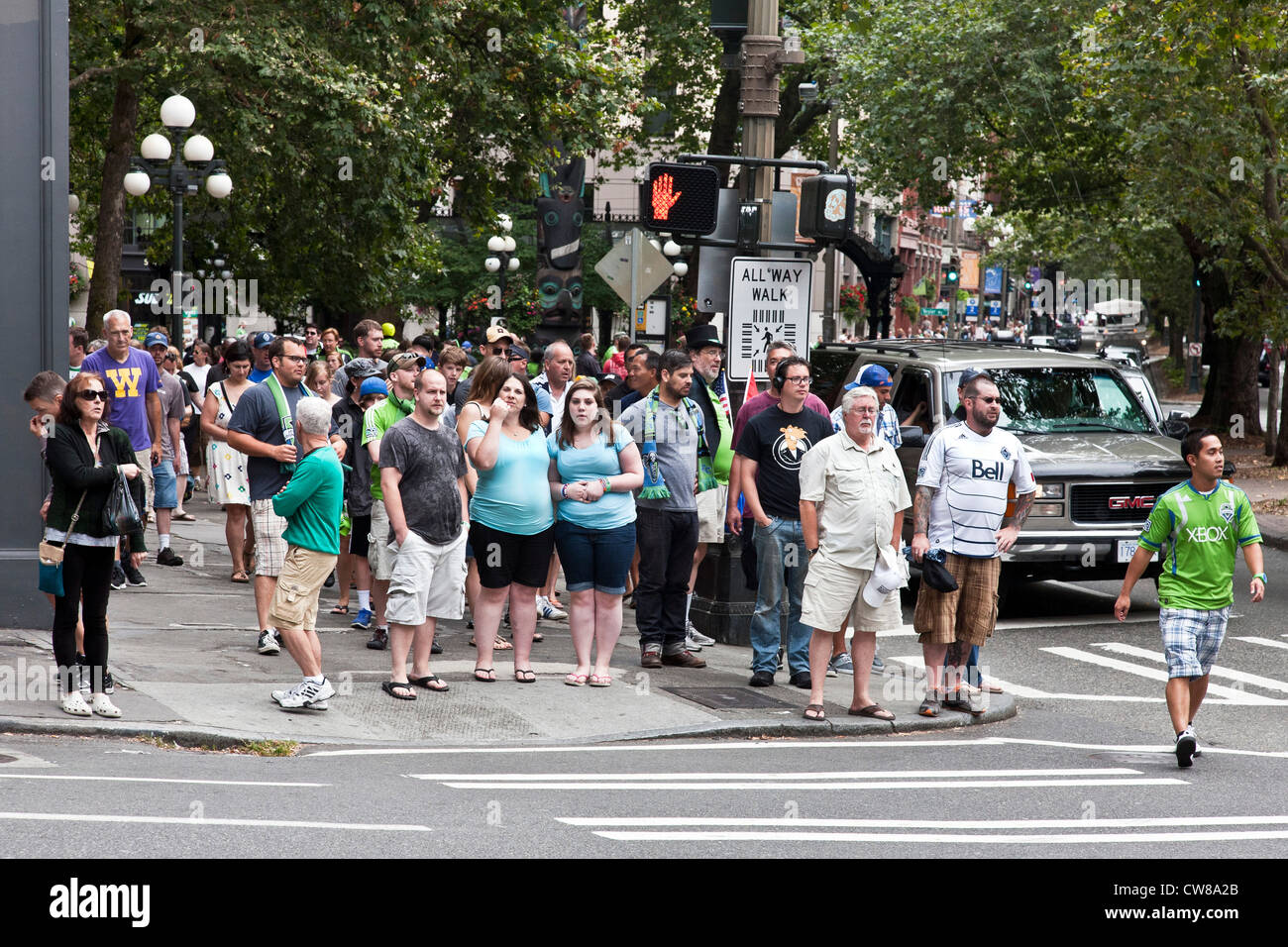 crowd Seattle Sounders soccer fans waiting to cross Pioneer Square at allway walk intersection after watching team defeat Vancouver White Caps Stock Photo