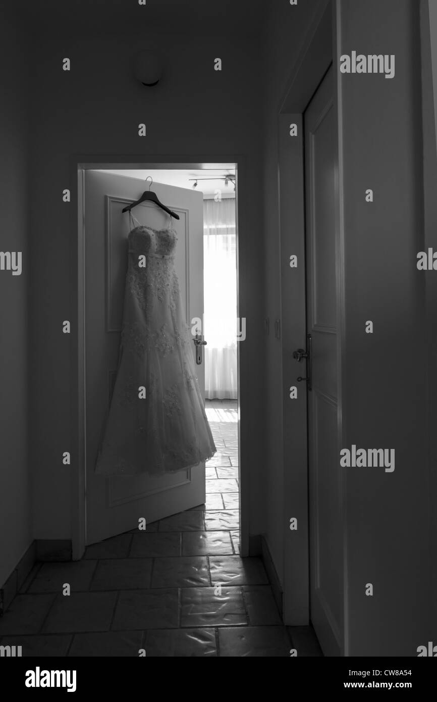 A prepared wedding dress hanging in front of the dressing room Stock Photo