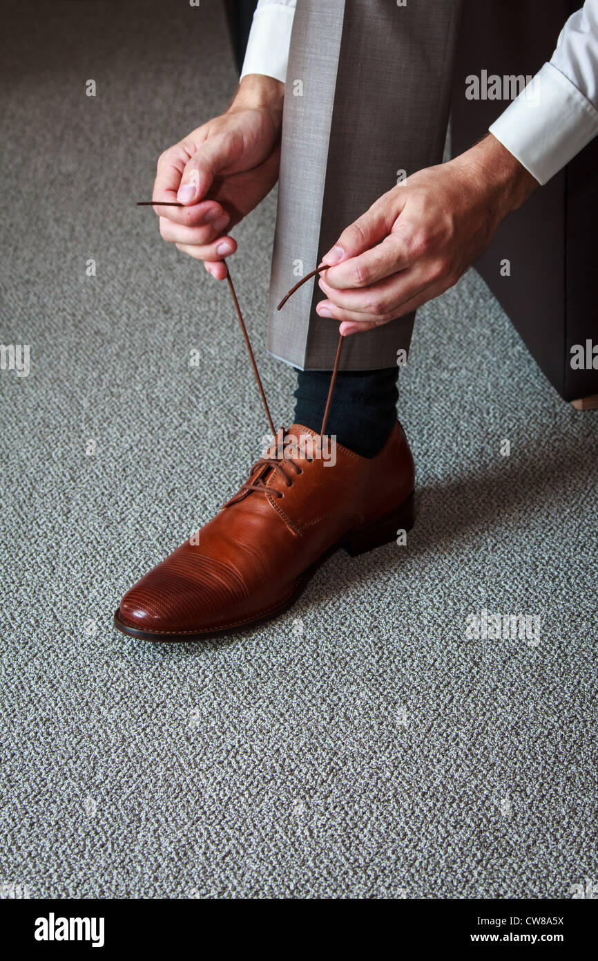 A young man tying elegant shoes indoors Stock Photo