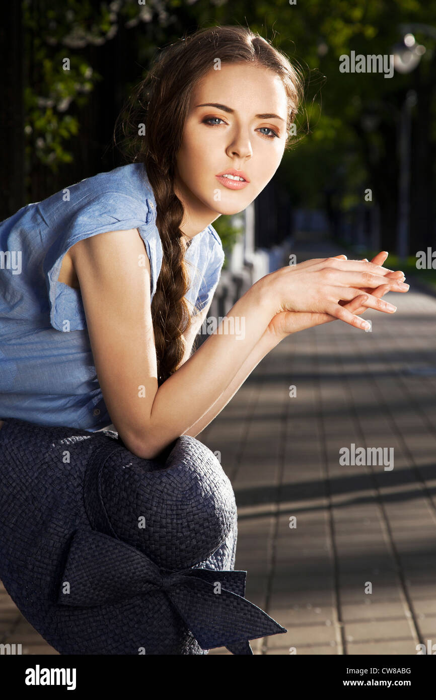 Portrait of a beautiful young girl with the hat on her legs sitting in