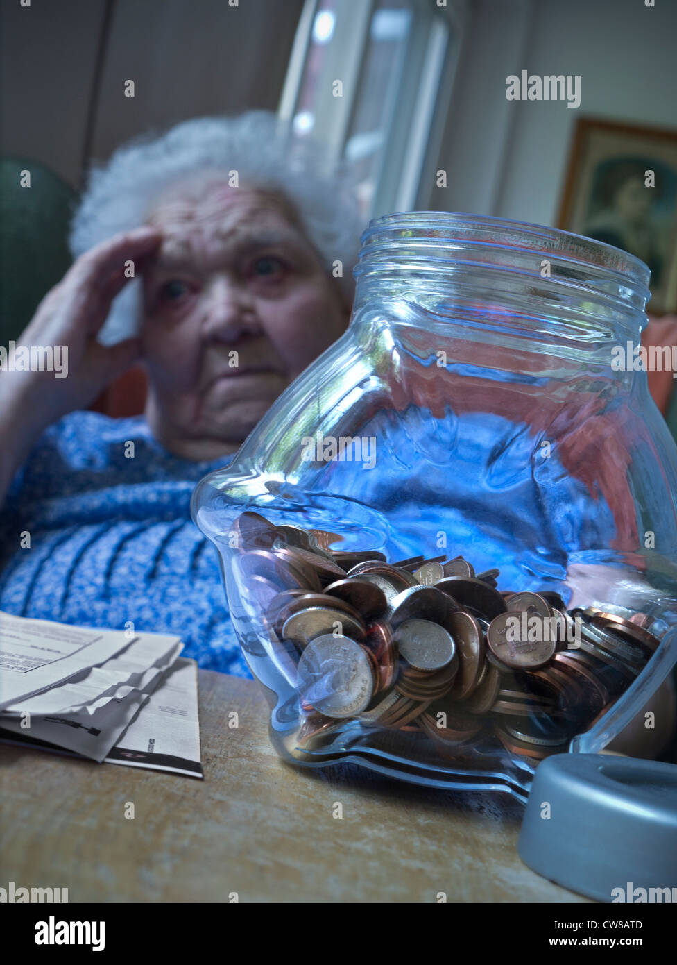 Money troubles senior elderly old age lady apprehensive with financial worries vulnerable, in her living room with savings pot and papers on table Stock Photo