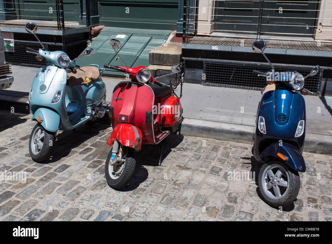 Three Vespa scooters parked on the street of New York City Stock Photo