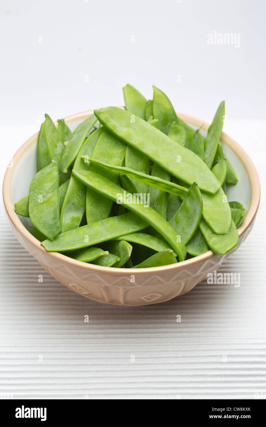 Mange Tout, Sugar snap Peas in bowl on plain Background Stock Photo
