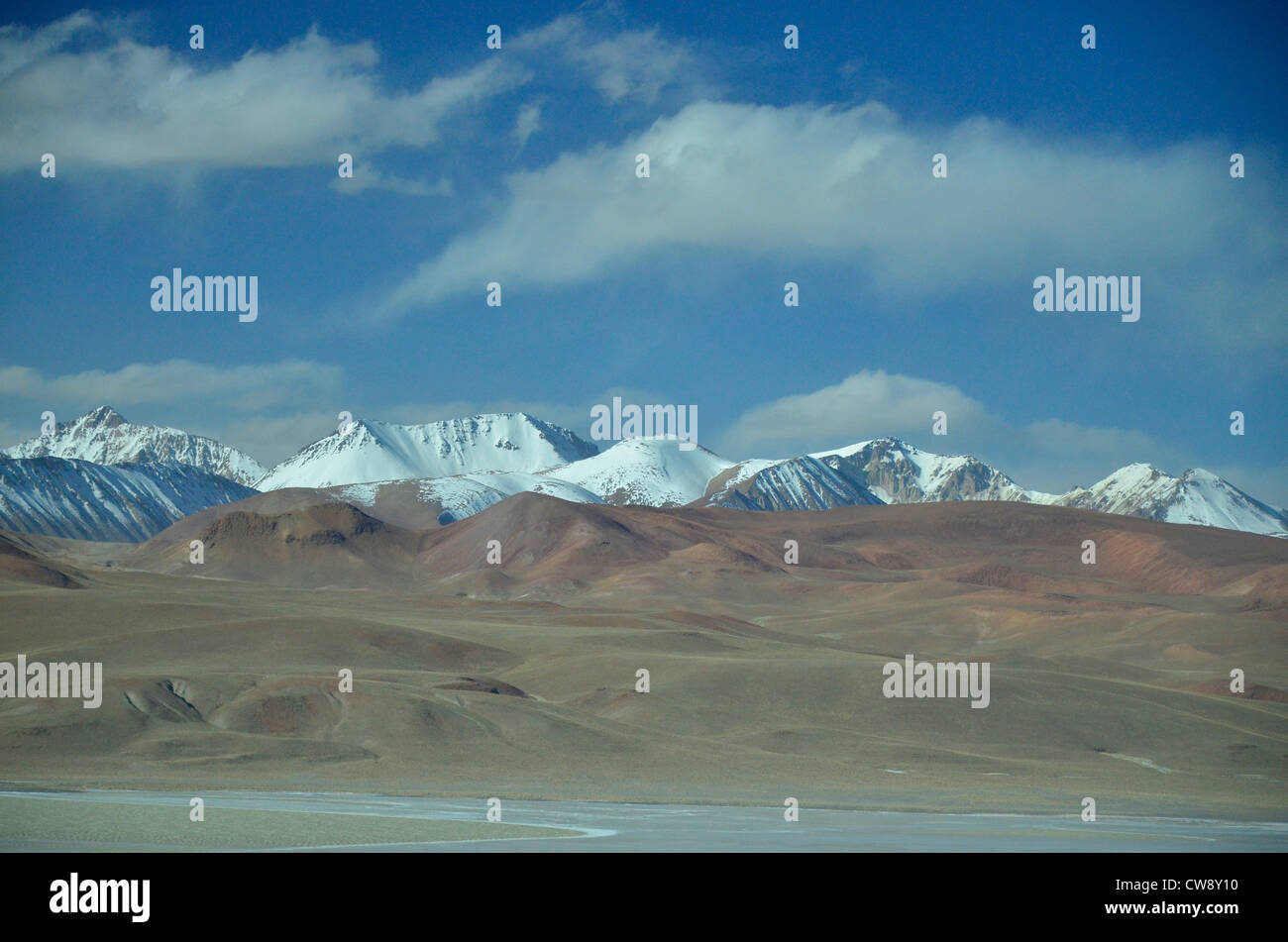 Touring the high altitude Altiplano of the Andes mountains in Bolivia, South America. Snowy mountaints, desert foreground, cloud Stock Photo