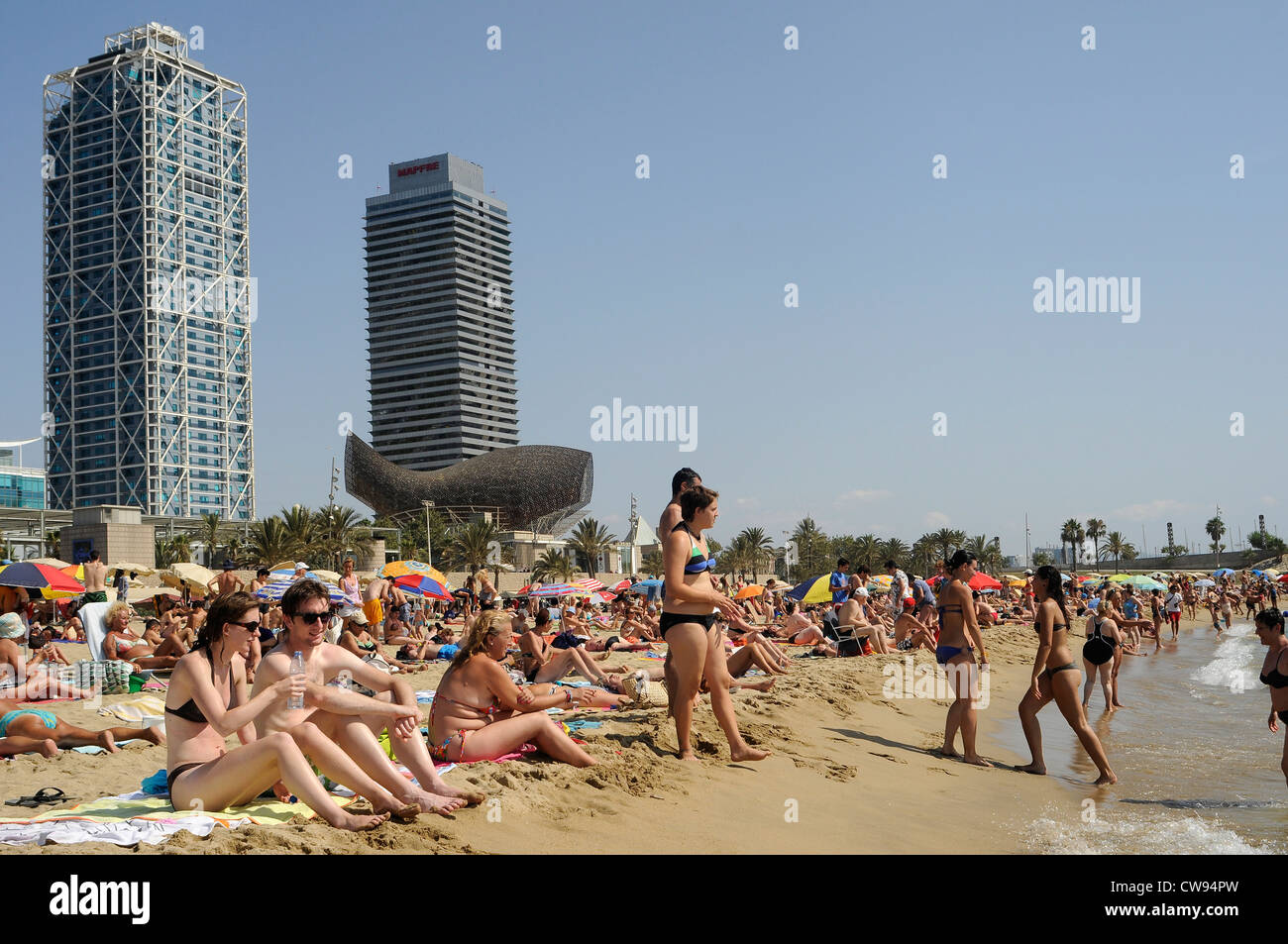 people on the beach , building of hotel arts designed by architect Bruce Graham of Skidmore, Owings & Merrill, fish by F. Gehry Stock Photo