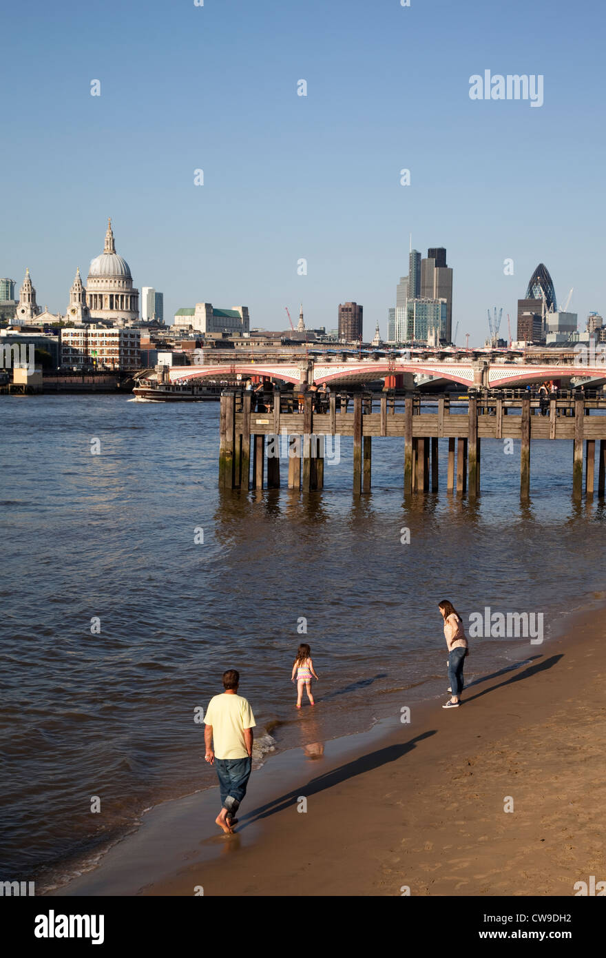A family walks on the sands exposed at low tide along the Thames, London Stock Photo