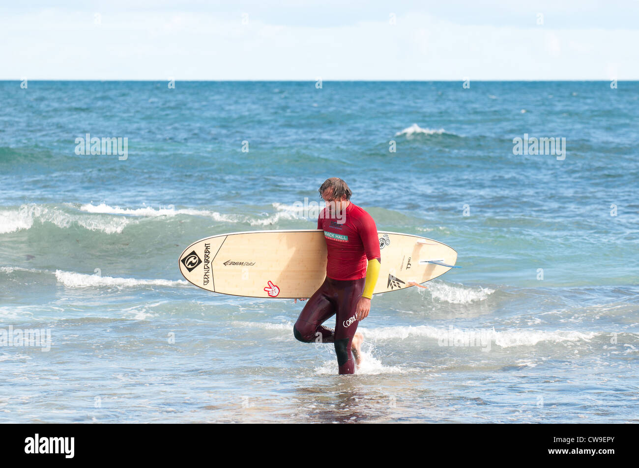 A surfer walking out of the sea at Isolators Reef in Western Australia.  WA. Australia. Stock Photo