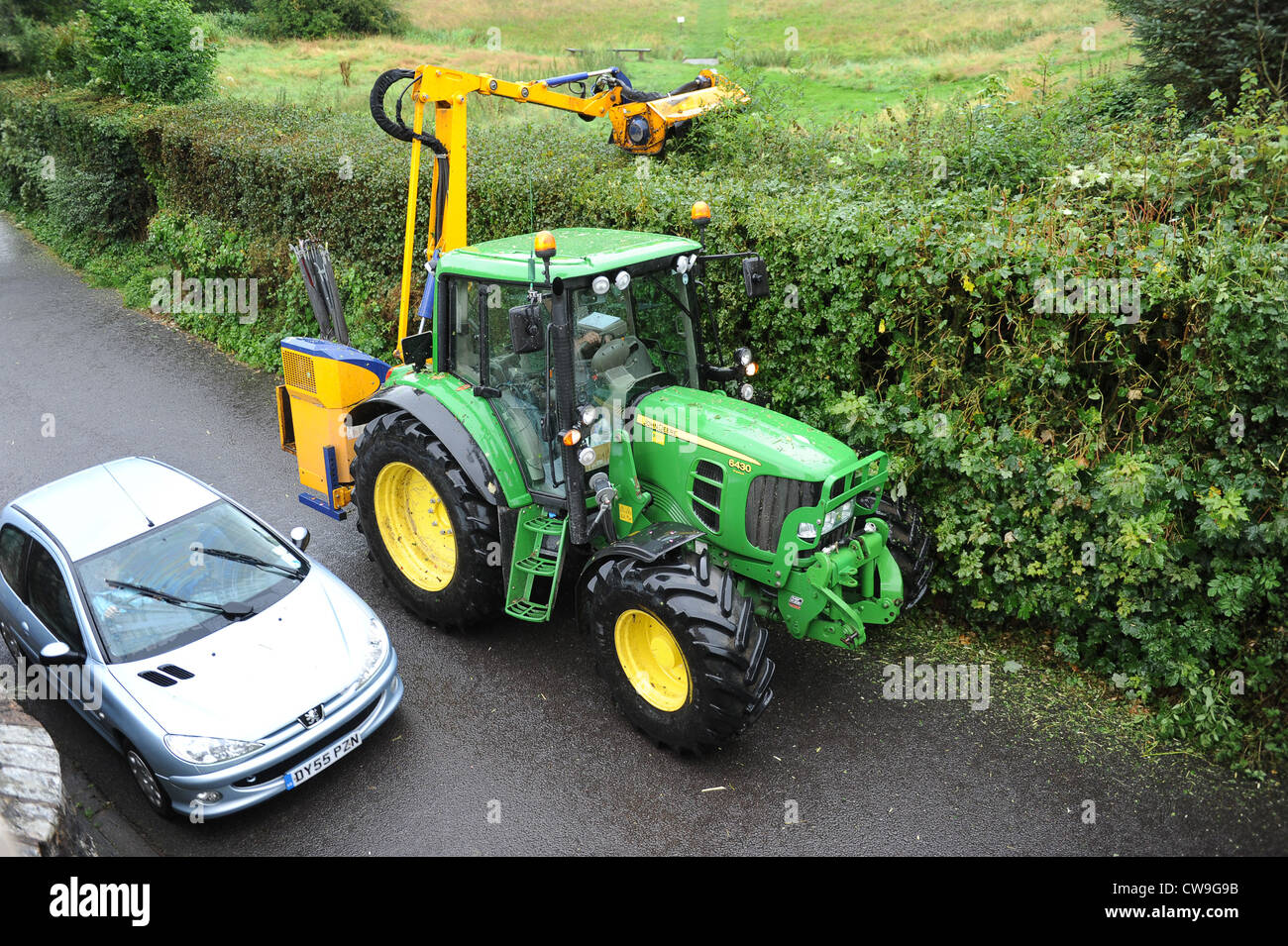 Car overtaking Tractor hedge cutting Uk Stock Photo