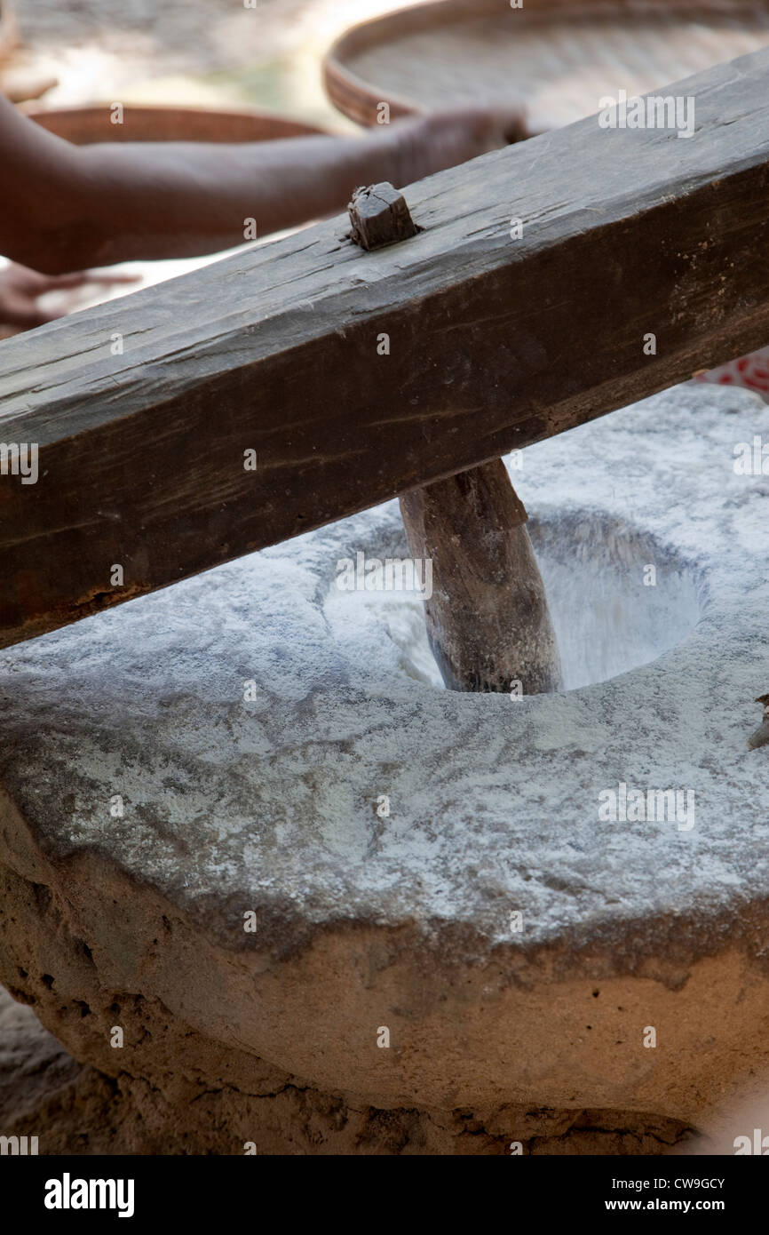 Myanmar, Burma. Wooden Pestle Pounding Rice in Stone Mortar, to Produce Rice Flour. Stock Photo