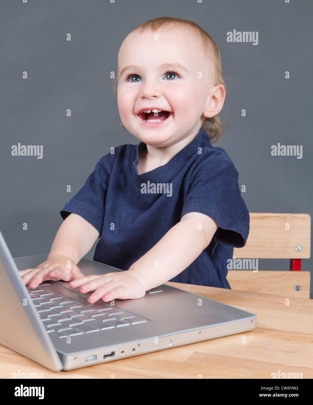 young child with laptop computer on wooden desk in grey background ...
