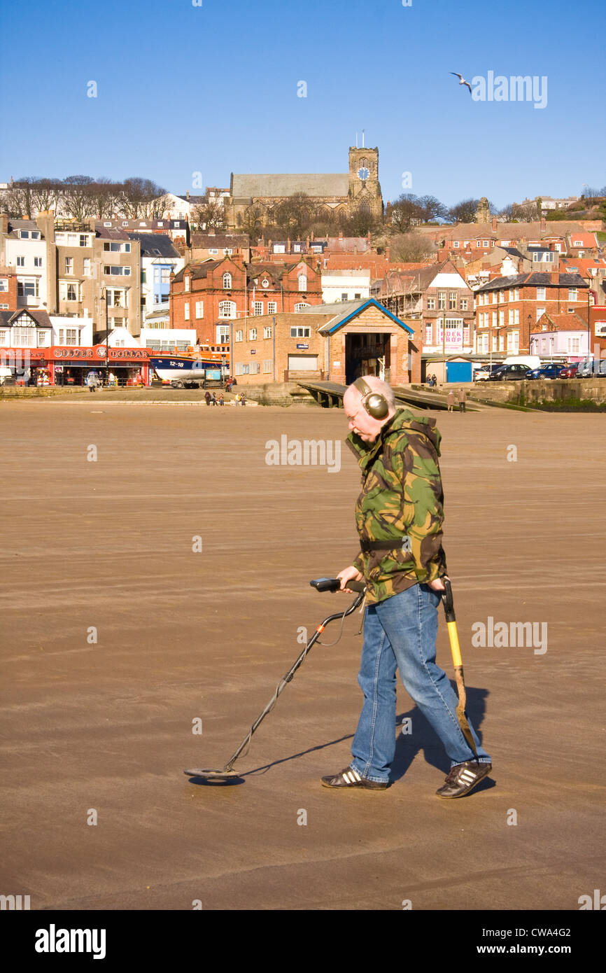 Man metal detecting on North Bay against backdrop of lifeboat station