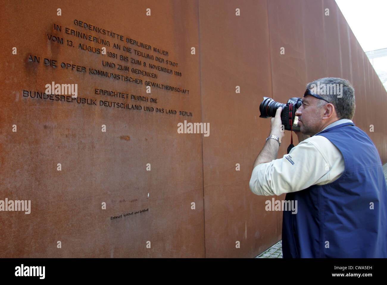 Berlin, a tourist photographed the memorial plaque in the park wall at Bernauer Strasse Stock Photo