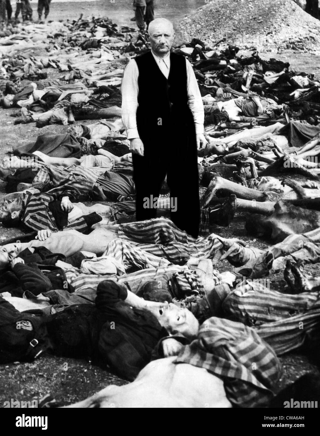 The commandant of the concentration camp in Landsberg, Germany stands amid some of the prisoners that were shot or burned as Stock Photo