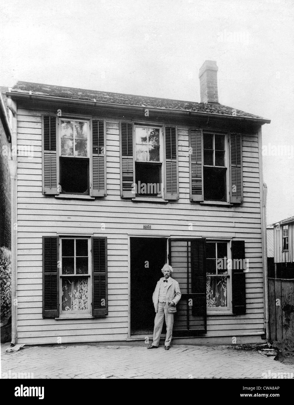 MARK TWAIN in front of his boyhood home in Hannibal, Missouri. Undate photo.. Courtesy: CSU Archives / Everett Collection Stock Photo