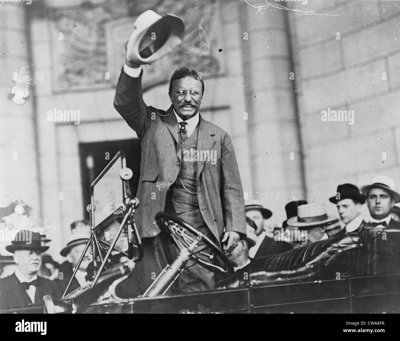 Theodore Roosevelt, waving his hat, as he stands in car. Ca. 1910. Stock Photo