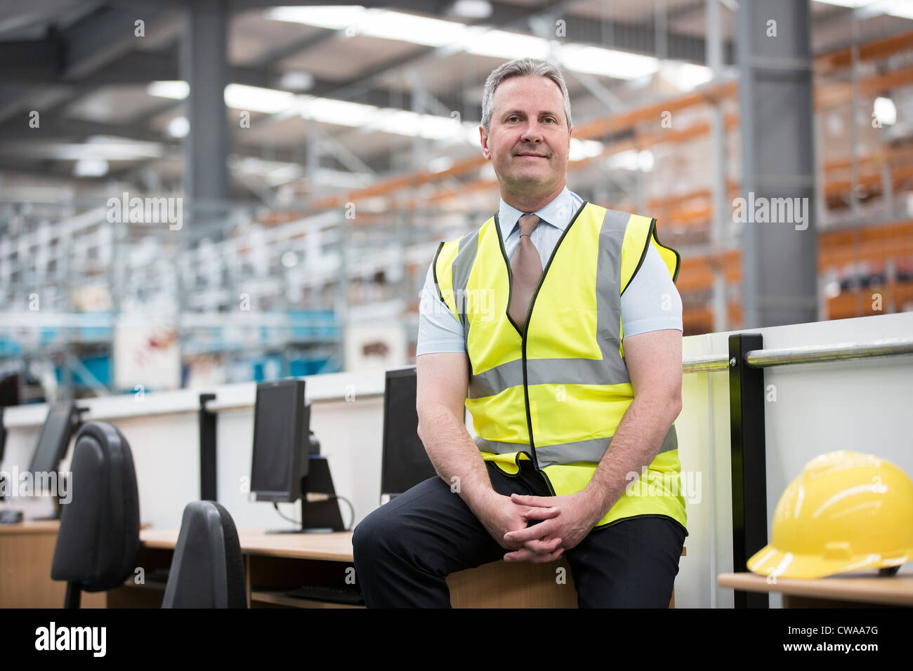 Man sitting on desk in warehouse, portrait Stock Photo