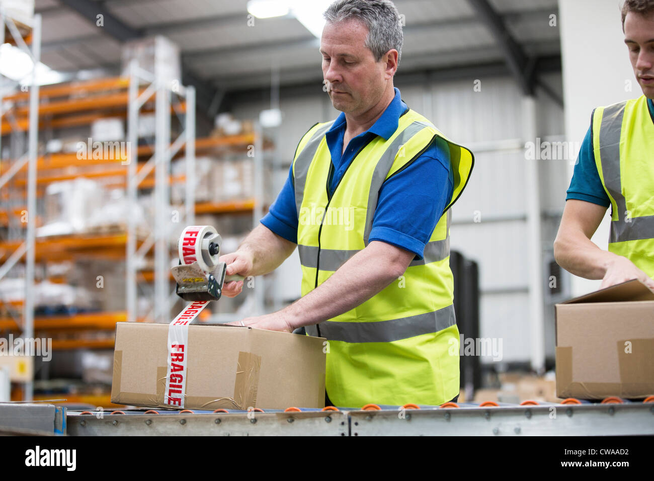 Men packing cardboard box in warehouse Stock Photo