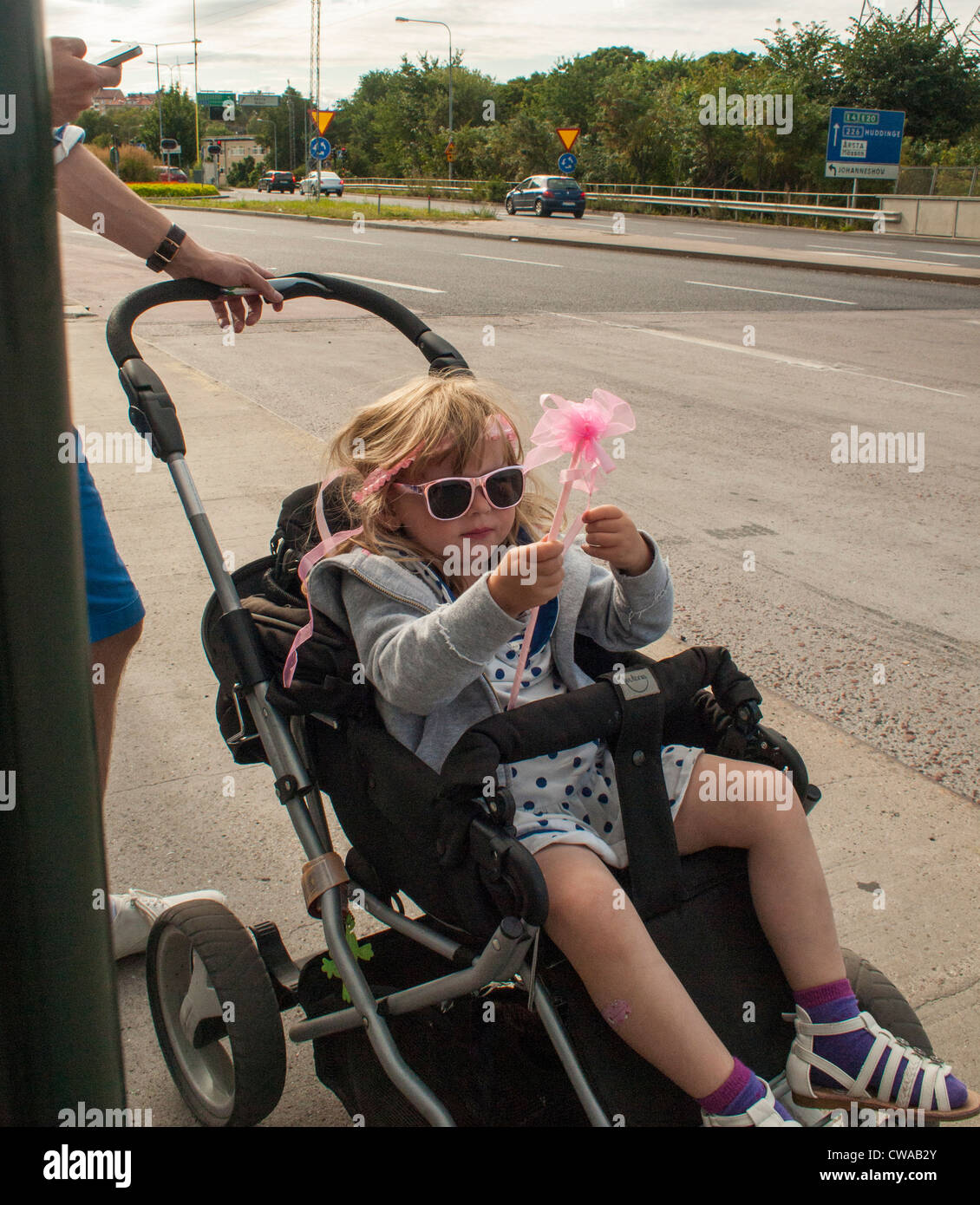 Small girl dressed as princess in a stroller waiting for the bus Stock Photo