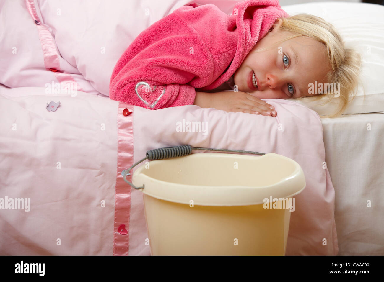 Ill girl in bed with bucket Stock Photo