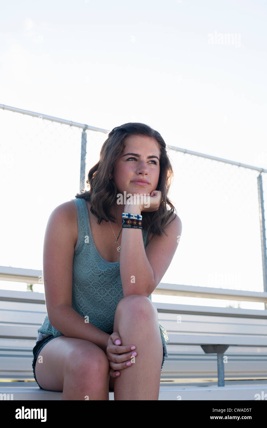 Teenage girl sitting on bleachers with hand on chin, portrait Stock Photo