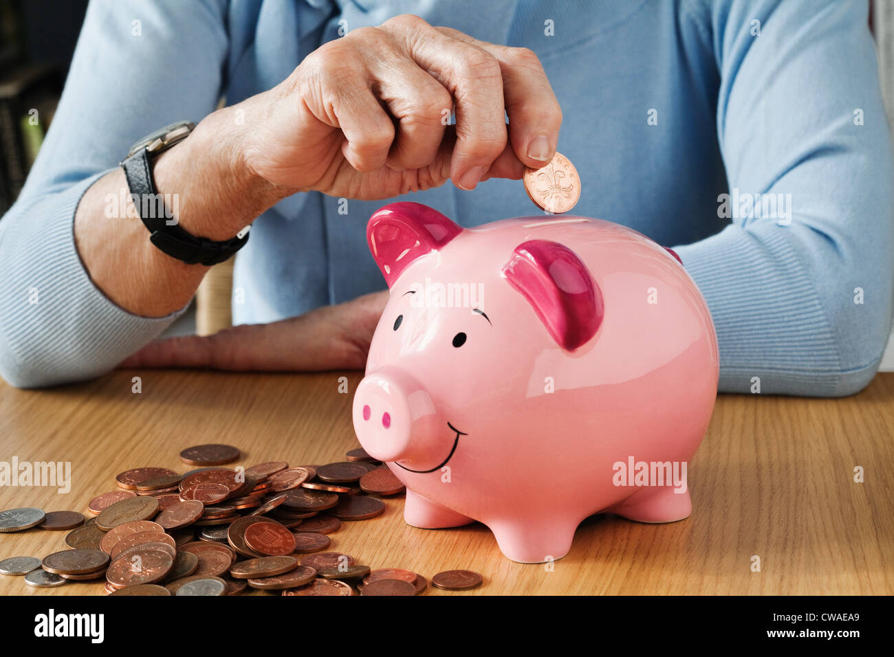 Senior woman inserting coins into piggybank Stock Photo - Alamy