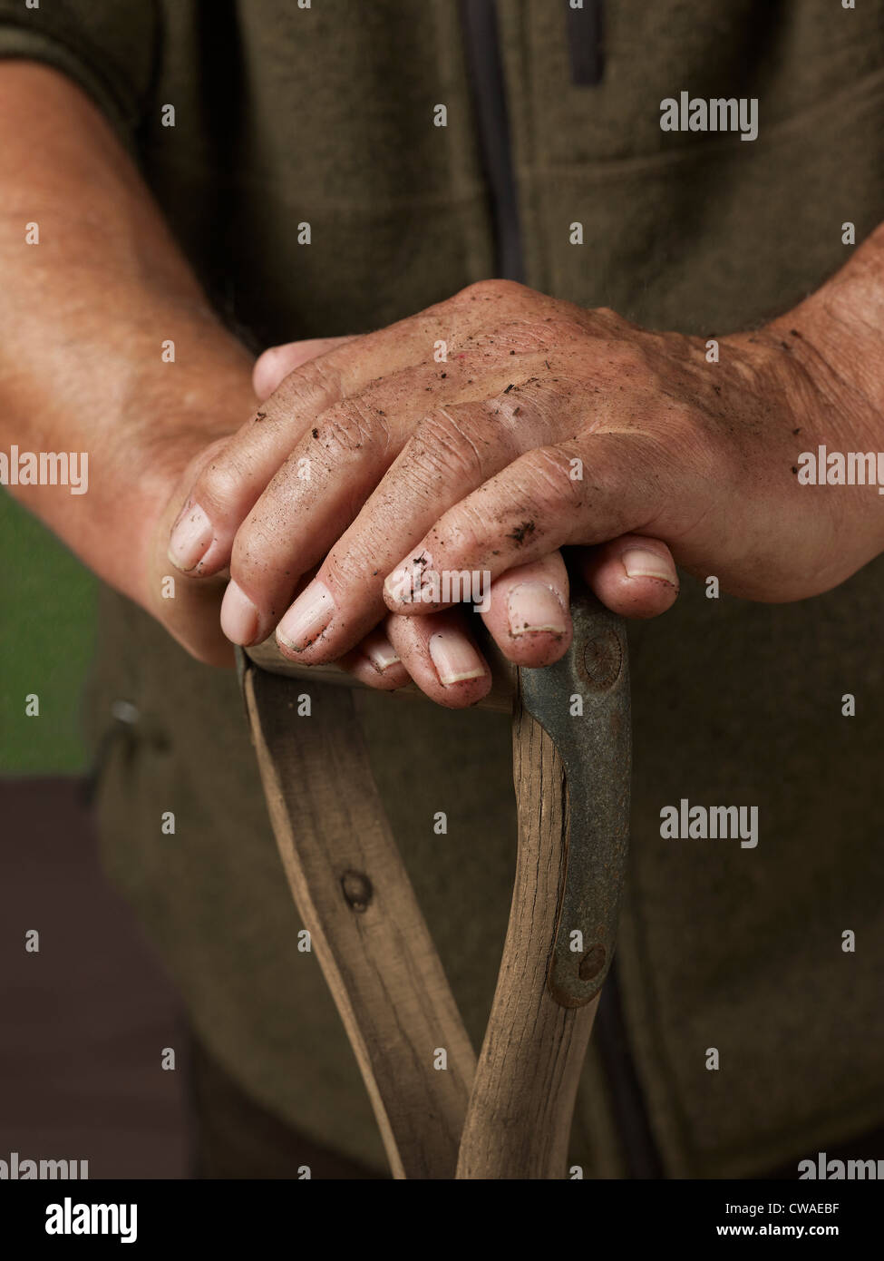 Man leaning with hands on wooden handle Stock Photo