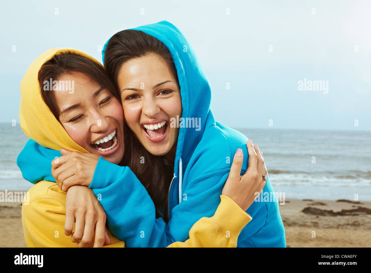 Two young women in hooded tops on beach Stock Photo
