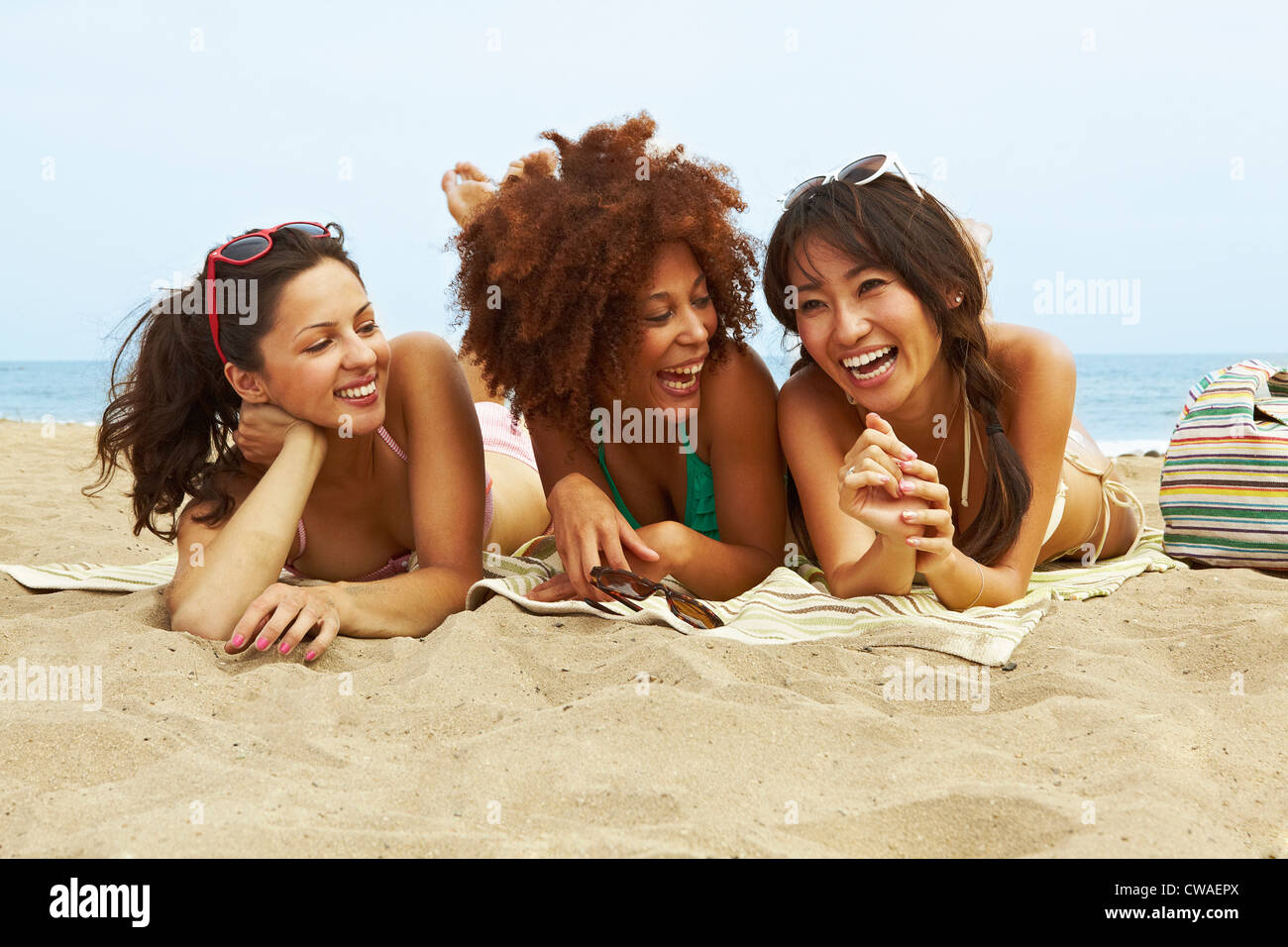 Young women sunbathing on beach Stock Photo