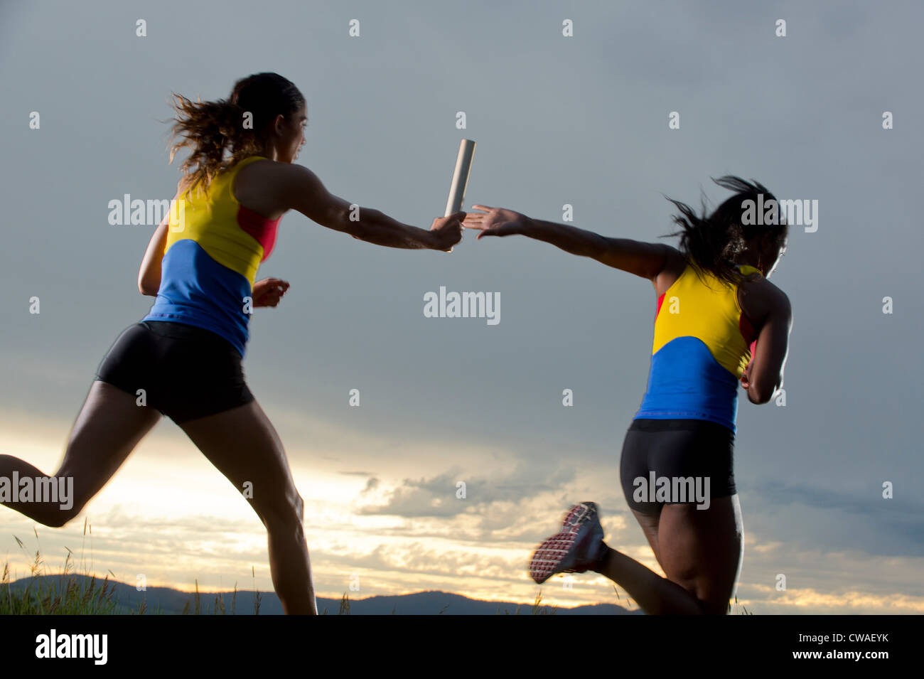 Female relay racers passing baton Stock Photo Alamy
