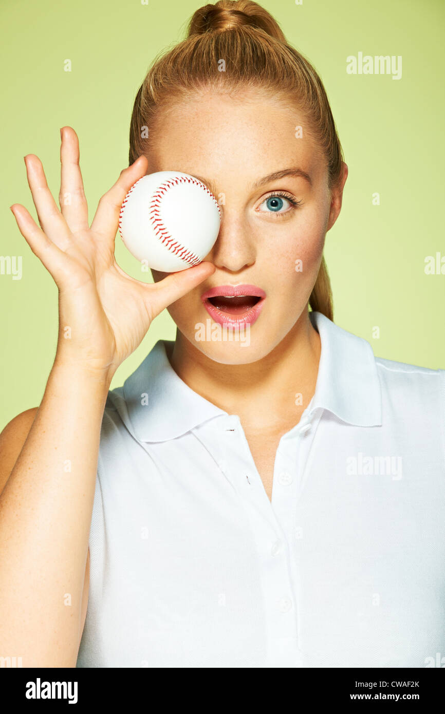 Young woman holding baseball in front of eye Stock Photo Alamy
