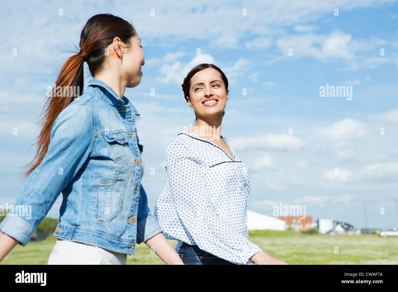 Two young women walking in field Stock Photo - Alamy